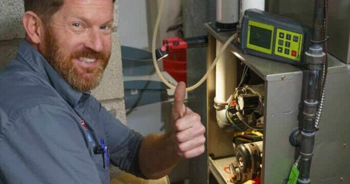 Repair Man Doing a Thumbs Up while Fixing a furnace